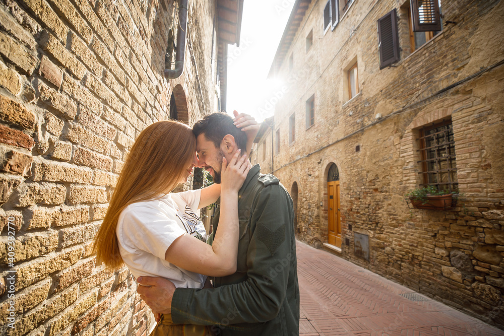 young beautiful couple travelers walking through the old town in Italy at sunset