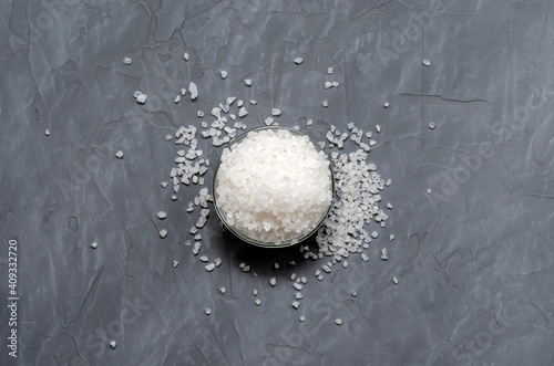 Bowl of coarse sea salt, on a gray concrete background, top view with place for text