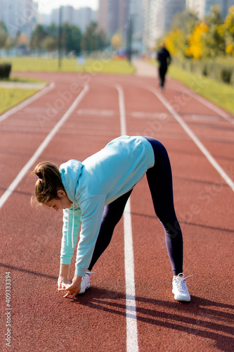 Outdoor fitness, public sports field. A young sportswoman does a workout on the street,