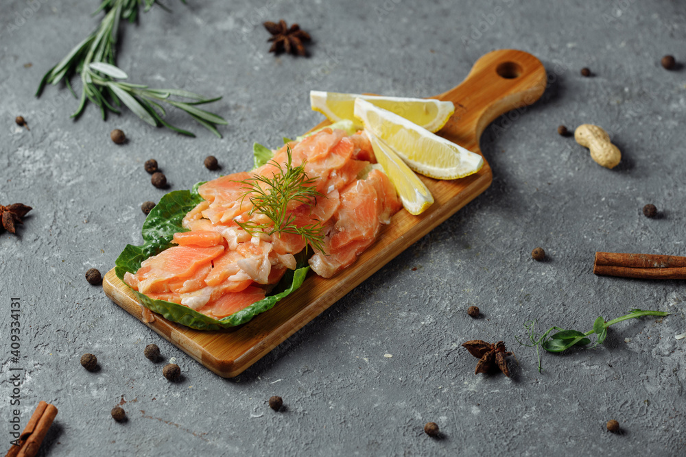 Pieces of fried salmon with dill and lemon wedges on a wooden board