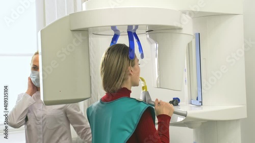 Doctor to take a image 3d scanner tomography of teeth and jaw in modern laboratory dental clinic. Female nurse shows the patient woman an x-ray machine 3d digital scanner. Computer dental diagnostics. photo