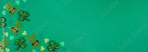St Patricks Day shamrock and leprechaun hat corner border. Overhead view over a green paper banner background with copy space.