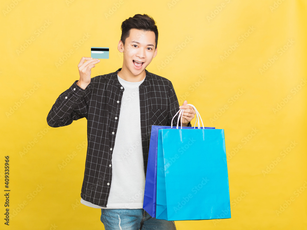 young man showing the credit card and shopping bags