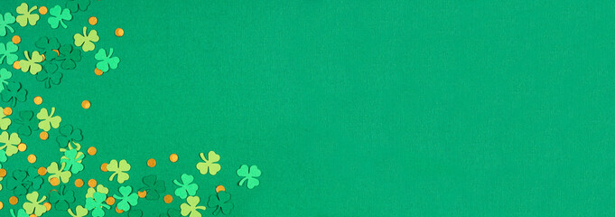 St Patricks Day green background with shamrock and gold coin confetti corner border. Overhead view banner with copy space.