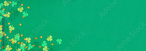St Patricks Day green background with shamrock and gold coin confetti corner border. Overhead view banner with copy space.