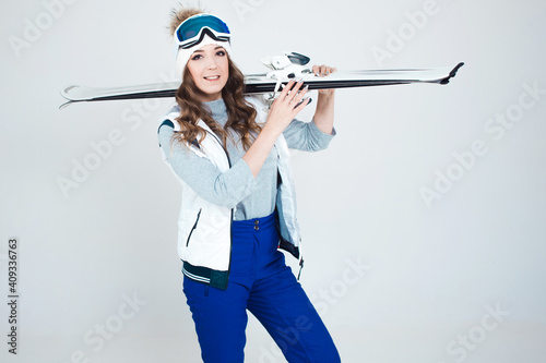 Smiling girl skier in a hat and mask for skiing. A young woman in clothes for skiing and outdoor activities. photo