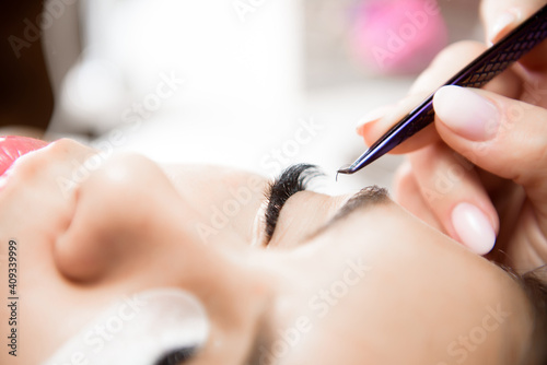 Beautiful young woman during eyelash extension, Close up.