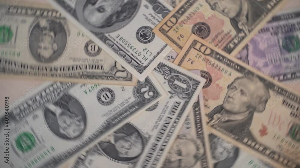 Green dollar bills lie stacked on a wooden round table and spin, slow motion Green dollar bills lie stacked on a wooden round table and spin, slow motion