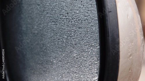 Blurred texture of car side mirror with water dots on glass surface. Frozen wet car mirror without heating in winter rain. Shiny raindrops over misted glass texture