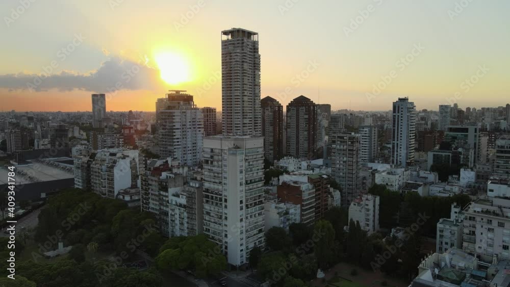 Dolly in flying over Palermo neighborhood skyscraper and buildings at sunset with bright sun shining through clouds, Buenos Aires, Argentina Dolly in flying over Palermo neighborhood skyscraper and buildings at sunset with bright sun shining through clouds, Buenos Aires, Argentina