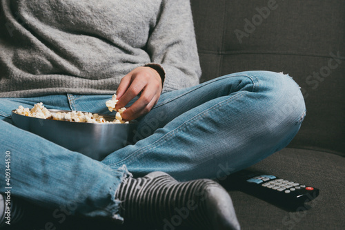Close-up of girl sitting on sofa with bowl of popcorn.