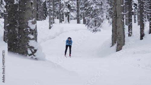 Slow motion shot of Professional athlethe cross country skier running on skis trough the frozeen forest covered in snow going downhill