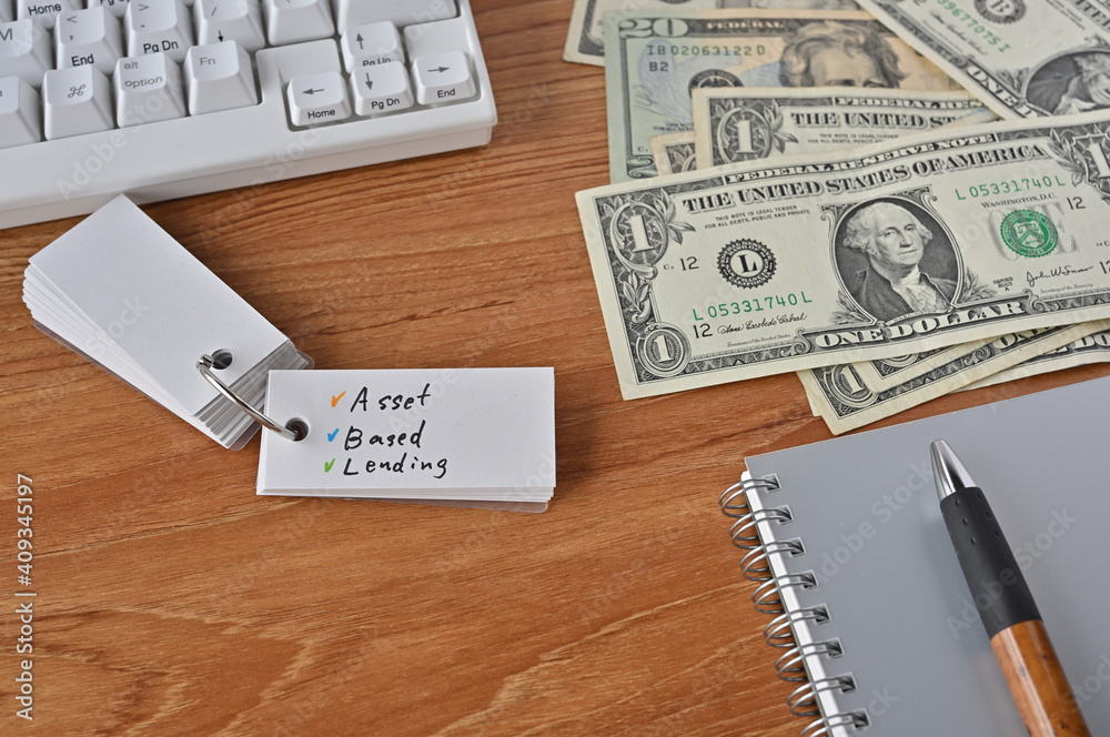 On the desk there were bills, a keyboard, and a word book with the word Asset Based Lending written on it. On the desk there were bills, a keyboard, and a word book with the word Asset Based Lending written on it.