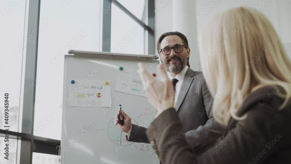 Confident male business trainer coach ceo leader give flip chart presentation at office training, businessman conference speaker wear suit explain strategy at corporate workshop Confident male business trainer coach ceo leader give flip chart presentation at office training, businessman conference speaker wear suit explain strategy at corporate workshop