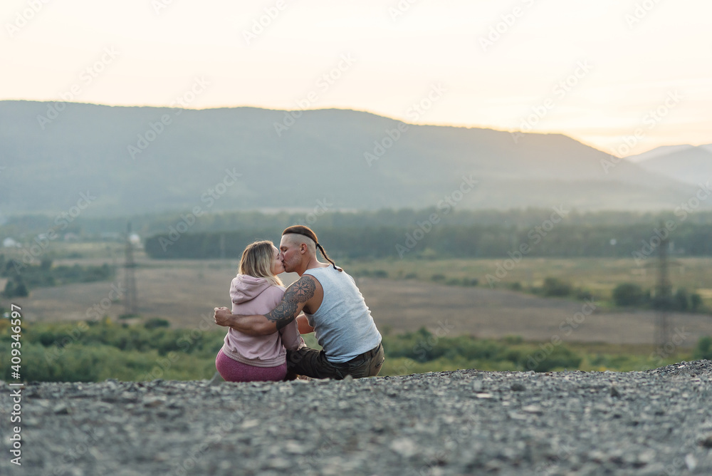 Young man hugs his girlfriend on the mountain peak at sunset background. Young man hugs his girlfriend on the mountain peak at sunset background.