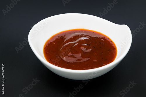 Red Souce in white dish on black, dark background
