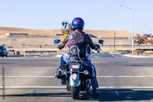 Back view of motorcyclist waiting at a traffic light; American flag attached at the back, waiving in the wind; San Francisco Bay Area, California