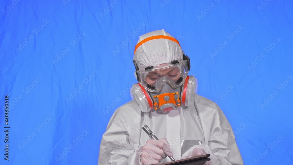 Scientist virologist in respirator makes write in an tablet computer with stylus. Woman wearing protective medical mask. Concept health safety virus coronavirus epidemic 2019 nCoV. Chroma key blue. Scientist virologist in respirator makes write in an tablet computer with stylus. Woman wearing protective medical mask. Concept health safety virus coronavirus epidemic 2019 nCoV. Chroma key blue.