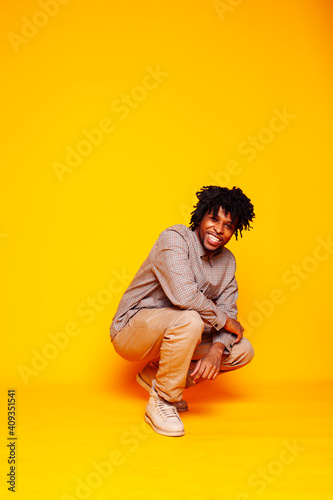 young handsome african american guy student posing cheerful and gesturing on yellow background, lifestyle people concept © iordani