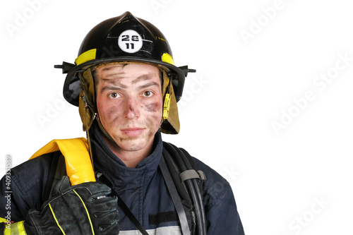 Close up of sweaty and dirty face of young brave man in uniform, hardhat of firefighter and with fire hose looking at camera isolated on white background © Serhii