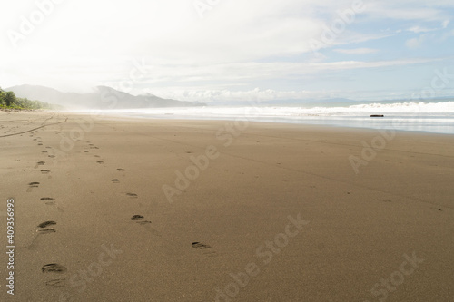 Paisaje con huellas en la arena de la playa junto al mar, un cielo hermoso y montañas en el Pacífico, Colombia