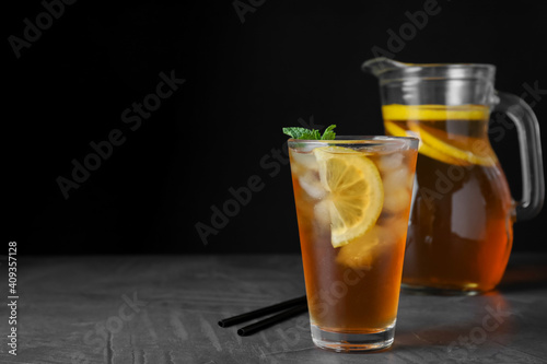 Delicious iced tea on grey table against black background, space for text