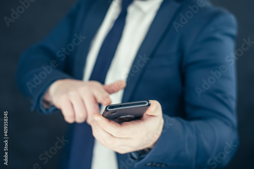 Businessman in a shirt and a blue jacket with smartphone in hand.