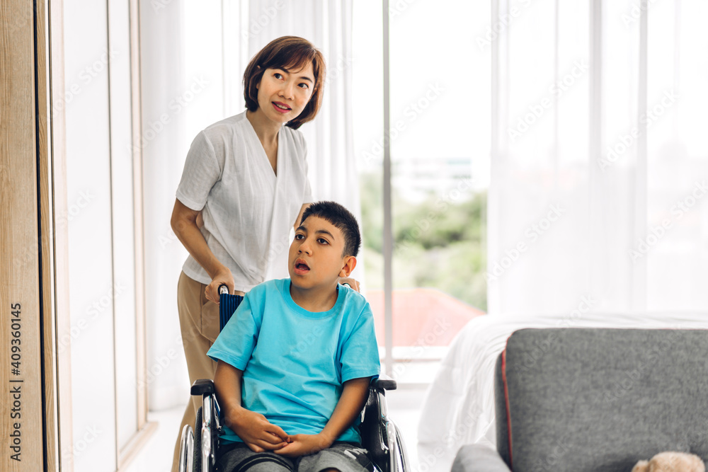 Portrait of enjoy happy love family asian mother playing and carer helping look at disabled son child sitting in wheelchair moments good time at home.disability care concept Portrait of enjoy happy love family asian mother playing and carer helping look at disabled son child sitting in wheelchair moments good time at home.disability care concept