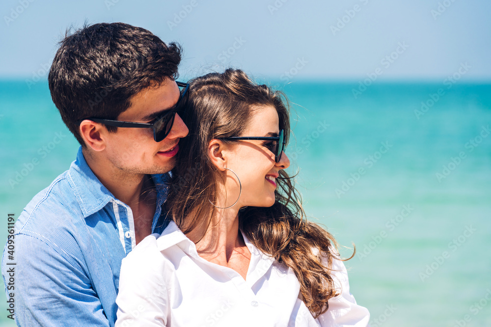 Vacation romantic love young happy couple hug and standing on sand at sea having fun and relaxing together on tropical beach.Summer vacations Vacation romantic love young happy couple hug and standing on sand at sea having fun and relaxing together on tropical beach.Summer vacations