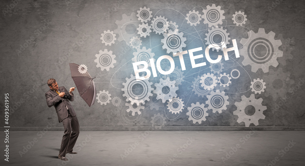 Businessman defending with umbrella from BIOTECH inscription, technology concept Businessman defending with umbrella from BIOTECH inscription, technology concept