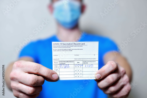 male is holding a vaccination record card and corona virus vaccine vials. Passport of immunity to the coronavirus in the hands of a male. Health passport as proof of recovery from COVID-19.