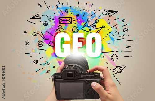 Close-up of a hand holding digital camera with abstract drawing and GEO inscription photo