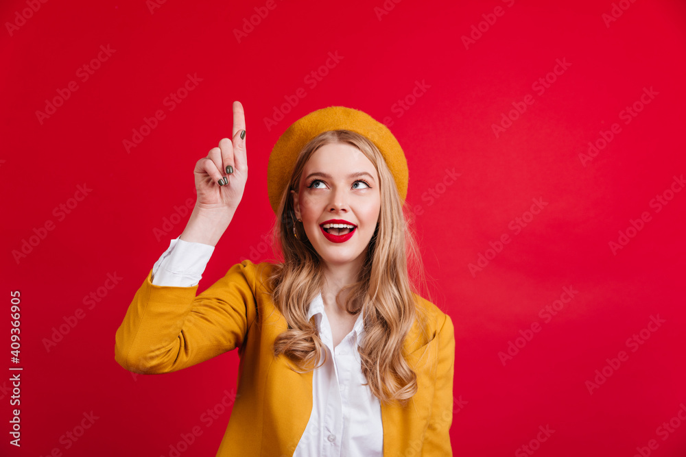 Curious french woman pointing with finger up. Studio shot of refined stylish girl in yellow beret. Curious french woman pointing with finger up. Studio shot of refined stylish girl in yellow beret.