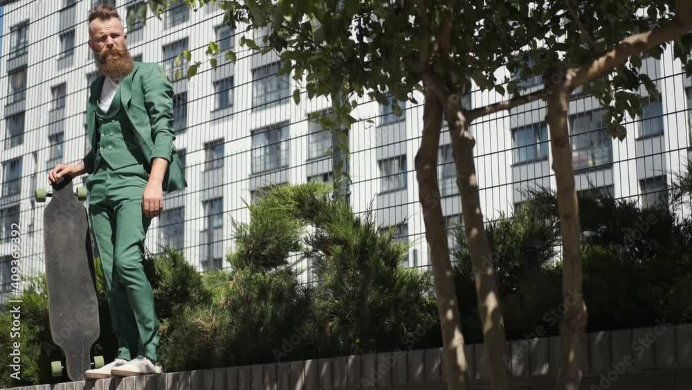 guy in green suit with longboard,walks in city, in park, young generation, modern style, sunny weather guy in green suit with longboard,walks in city, in park, young generation, modern style, sunny weather