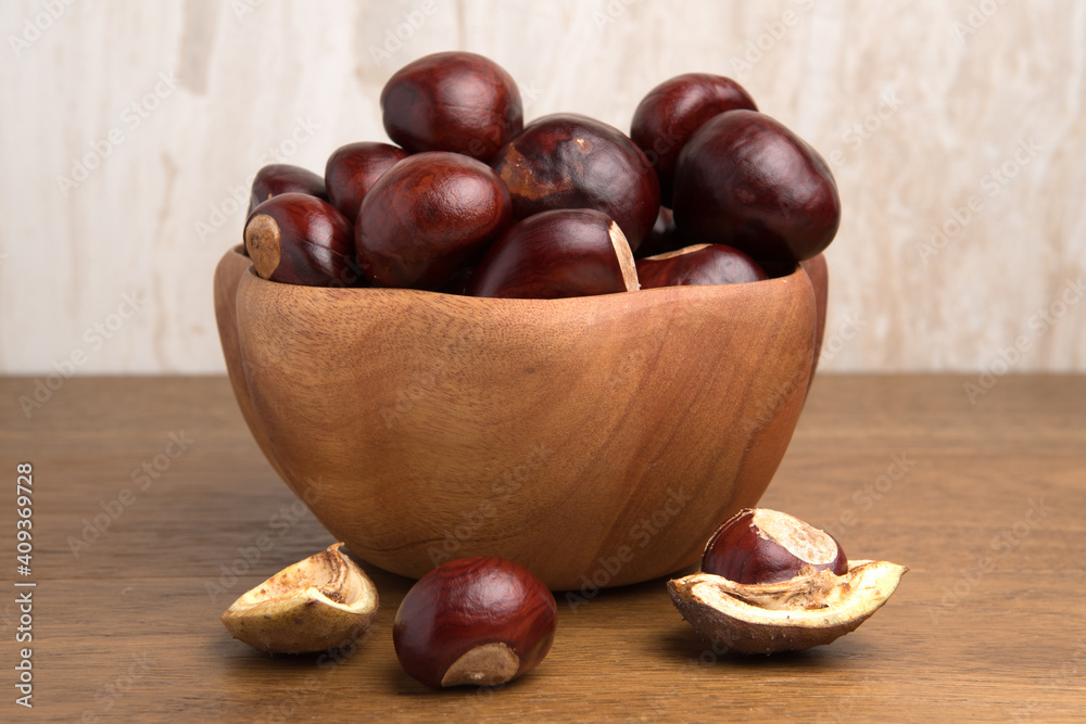 Buckeye Chestnut in wooden bowl on wooden surface. Side View formation of Fresh conkers. Buckeye Chestnut in wooden bowl on wooden surface. Side View formation of Fresh conkers.