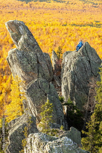 mature tourist posing on the rocks of the mountain round hill on the Alabiya ridge in the Ural mountains on an autumn sunny day. photo