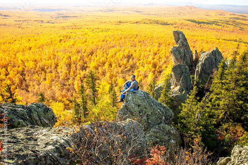 mature tourist posing on the rocks of the mountain round hill on the Alabiya ridge in the Ural mountains on an autumn sunny day. photo