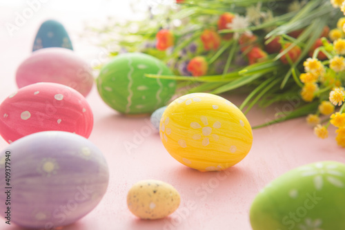 Easter eggs with wild flowers on a wooden pink table background