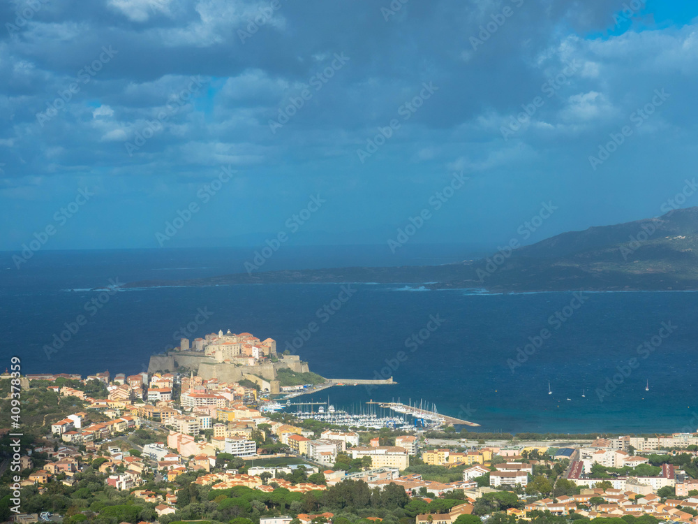 Aerial view of the port of Calvi with dramatic sky. ​​Corsica, France. Tourism and vacations concept.