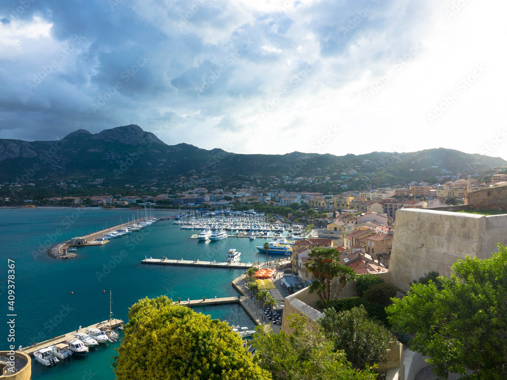 Aerial view of the port of Calvi with dramatic sky. ​​Corsica, France. Tourism and vacations concept.