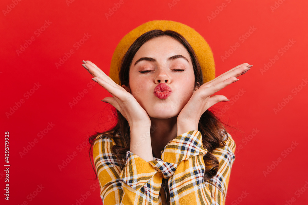 Close-up portrait of pink-cheeked girl sending air kiss. Woman in checkered blouse posing with closed eyes in romantic mood Close-up portrait of pink-cheeked girl sending air kiss. Woman in checkered blouse posing with closed eyes in romantic mood