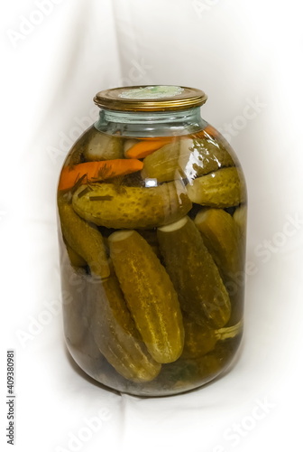 Pickles in a rolled-up metal lid three-liter glass jar on a white background