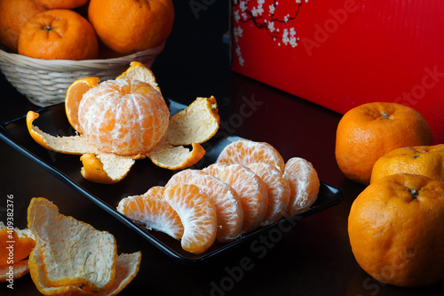 Tangerine or mandarin orange, peeled arranged with the fruits and a red box at background - suitable for Chinese New Year celebration graphic resource photo