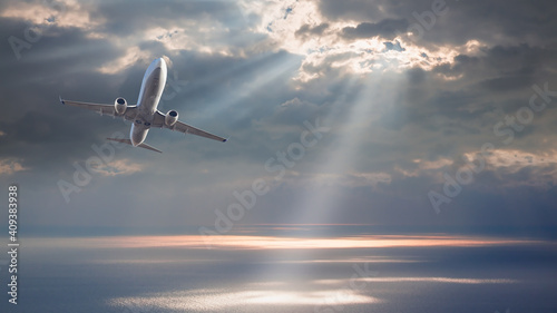 Commerical airplane flying over tropical sea at sunset