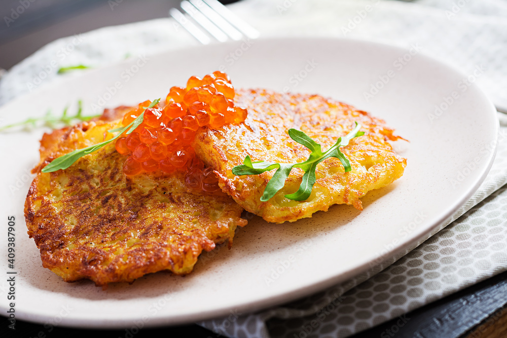 Fried potato pancakes with red caviar and sour cream, fritter, roesti. Traditional delicious food, lunch.