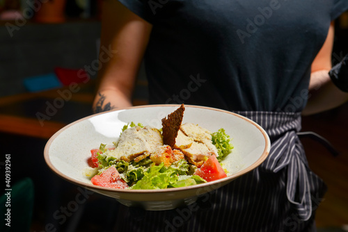 Traditional Caesar salad served by waiter in restaurant or diner. Delicious meal for dinner  eating out concept