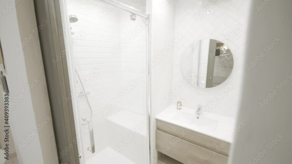 interior design wide view of a bright white bathroom with tall shower and sink. interior design wide view of a bright white bathroom with tall shower and sink.