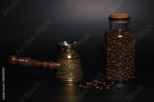 Turkish coffee pot with coffee beans in a jar, isolated on a black background