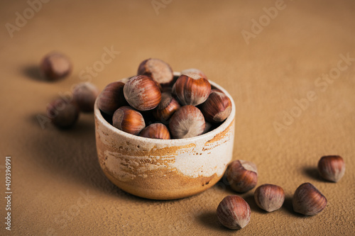 Pile of hazelnuts filbert in a bowl on a brown background. Fresh nuts in their shells. photo