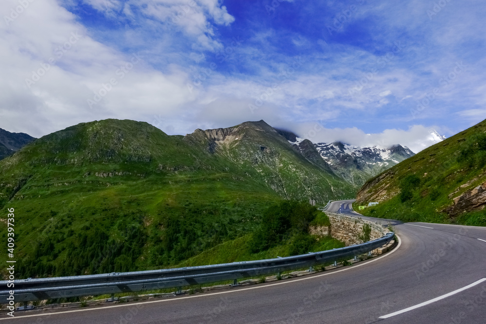 high curvy road in green mountains with blue sky